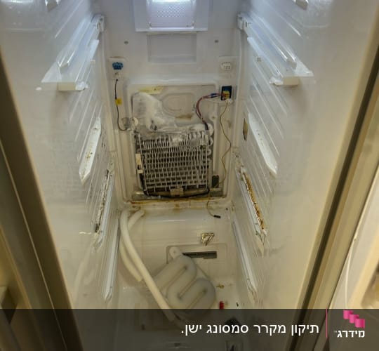 תא מקרר פתוח עם כלים וחלקים פנימיים חשופים